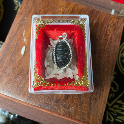 Crow bezoar mustika pendant held in hand for size